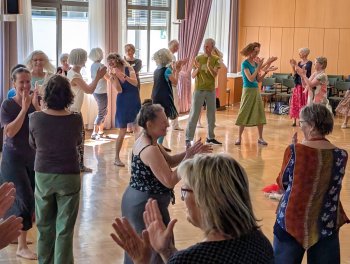 Die linke und rechte Nachbarin klatschend begrüßen - Beginn mit Andrea